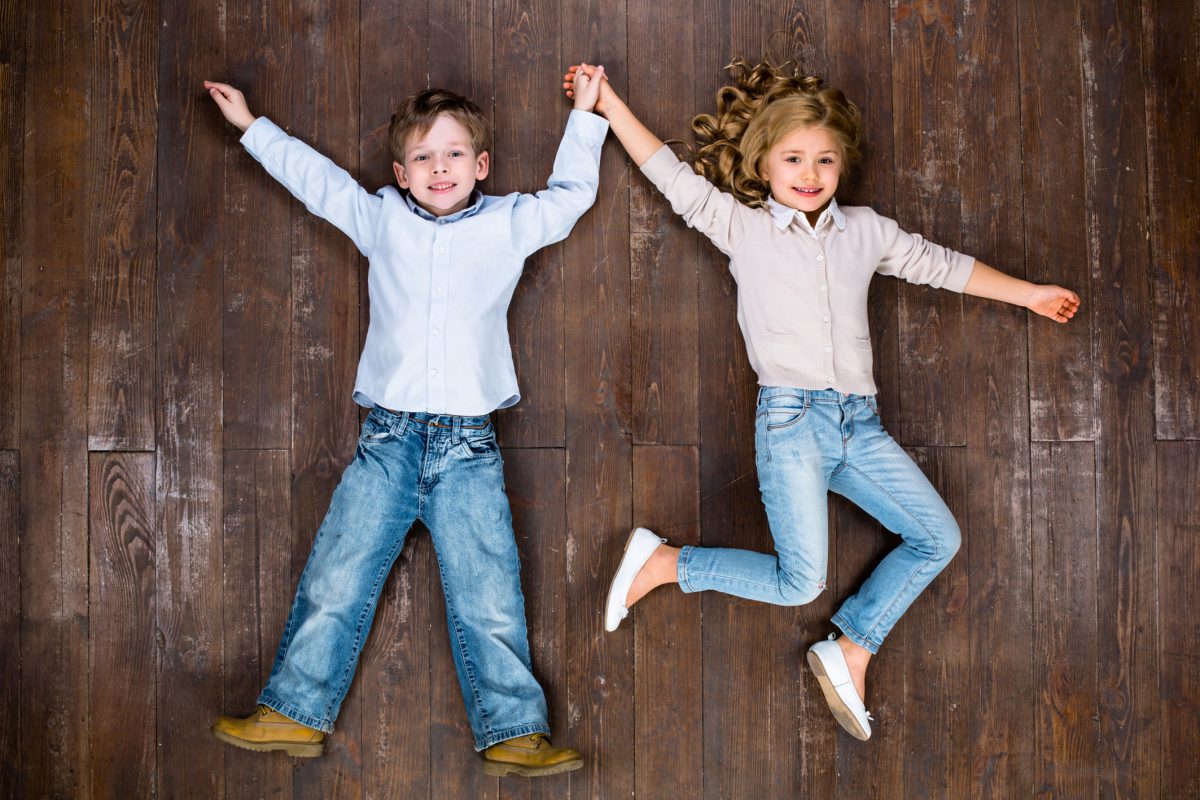 Happy children. Top view creative photo of little boy and girl on vintage brown wooden floor. Children looking at camera and smiling